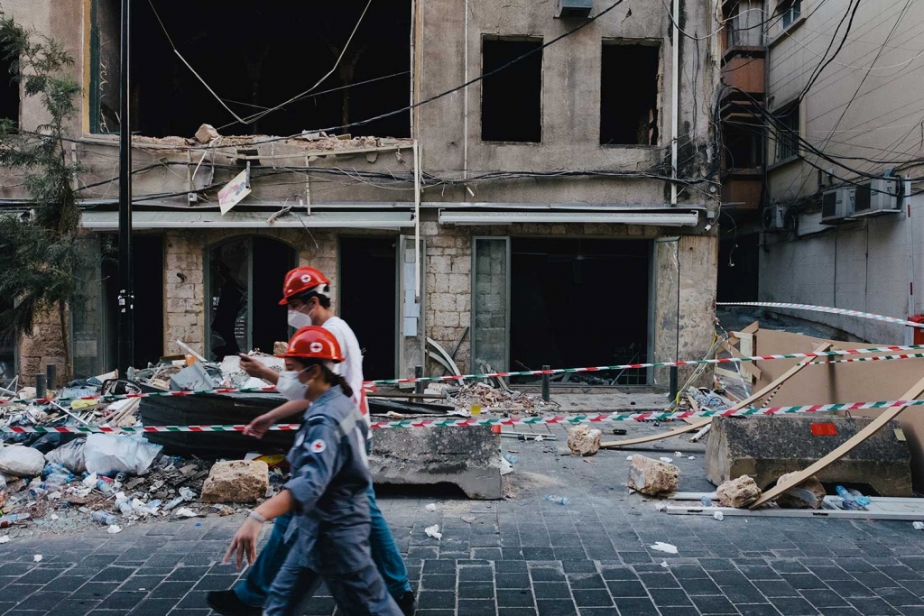 Deux personnes dans la rue devant un immeuble détruit à Beyrouth.