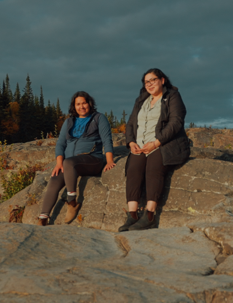 Uapukun Mestokosho et Shanice Mollen Picard sont assises sur des rochers.